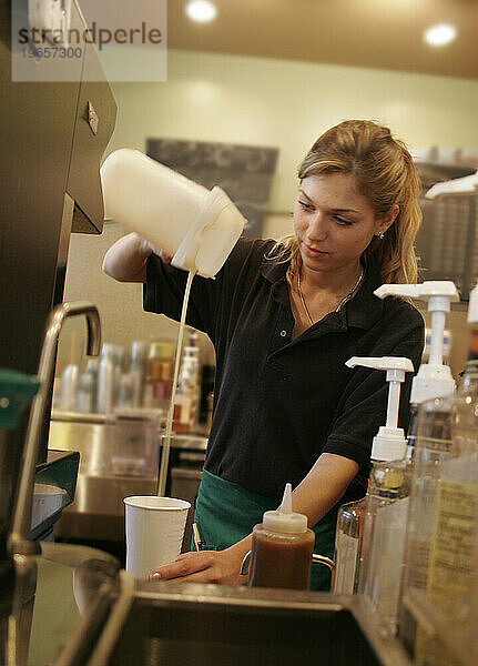 Eine Arbeiterin bereitet einem Kunden in einem Café ein Getränk zu.