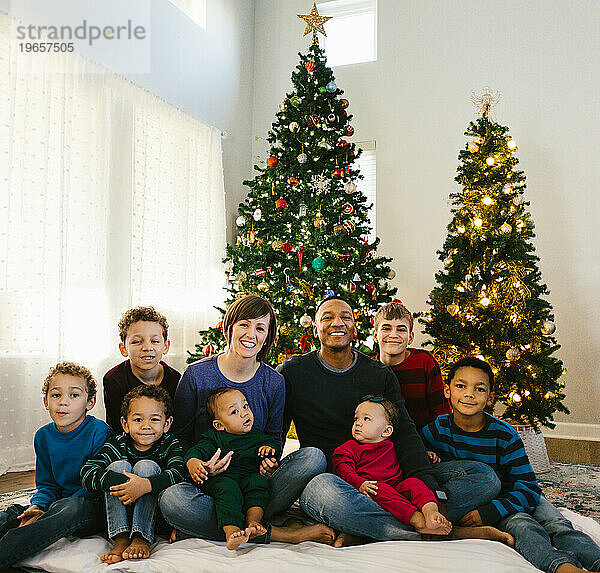 Vielfältige Familie zusammen unter Weihnachtsbäumen in ihrem Haus