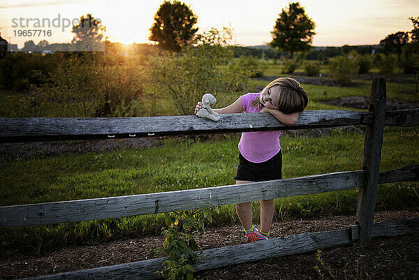 Kleines Kind lächelt über ausgestopftes Lammspielzeug im sonnigen Feld