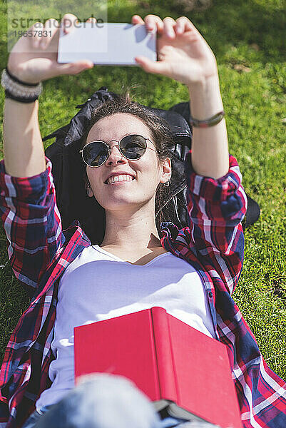 Oben Ansicht einer jungen lächelnden Hipster-Frau  die auf Gras liegt