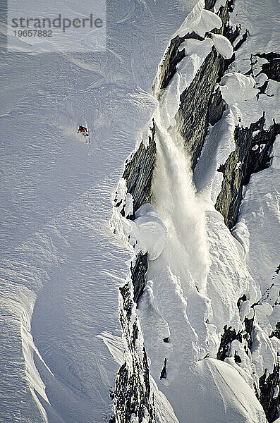 Ein Mann  der in der Nähe einer Klippe Ski fährt und eine Spindriftlawine verursacht  Alaska.