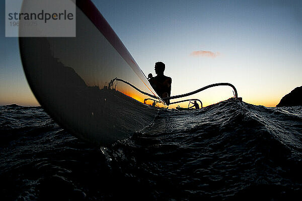 Silhouette zweier Auslegerkanu-Paddler bei Sonnenuntergang aus der Perspektive eines niedrigen Winkels.