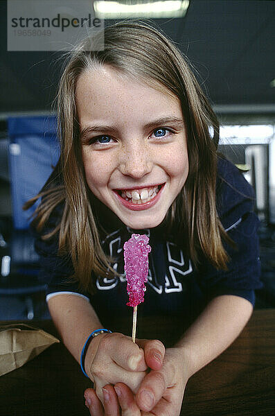A little girl holds onto her lollipop tightly.