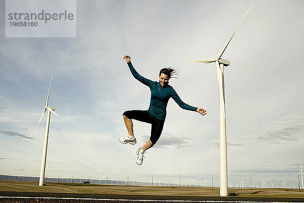 Eine Frau springt in die Luft  im Hintergrund Windmühlen.