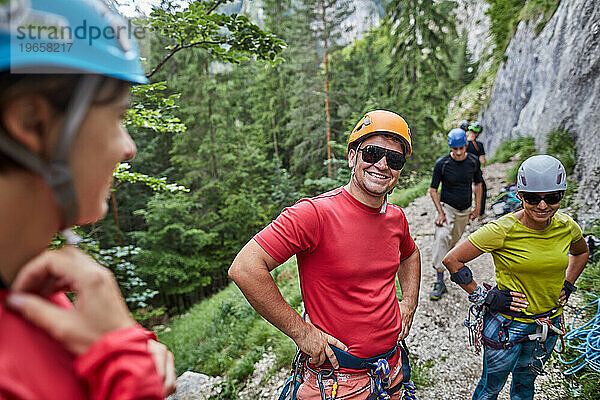 Ein lachender Kletterer in einer Gruppe von Kletterern steht neben einem Felsen