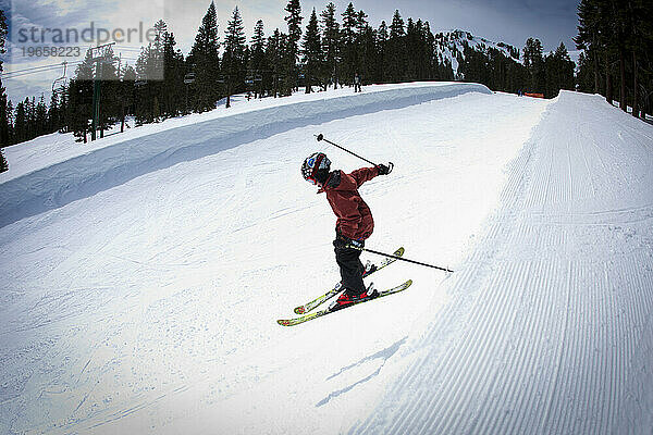 Junger Skifahrer fällt in eine Halfpipe.