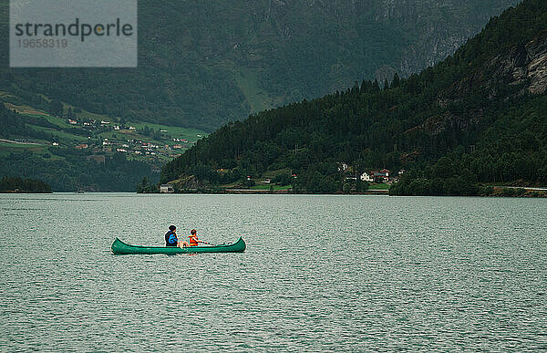 Mutter und Sohn beim Kanufahren in einem norwegischen Fjord an einem regnerischen Tag