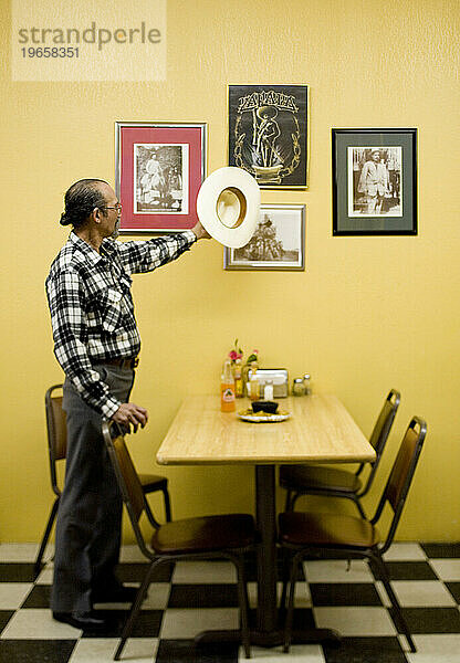 Ein Porträt eines lateinamerikanischen Mannes und seines Cowboyhutes in einem Restaurant.