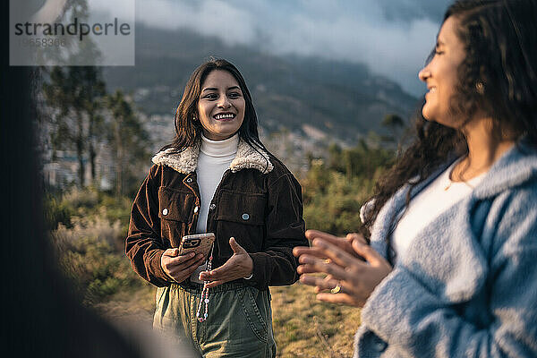 Zwei Latina-Frauen unterhalten sich bei Sonnenuntergang fröhlich im Freien
