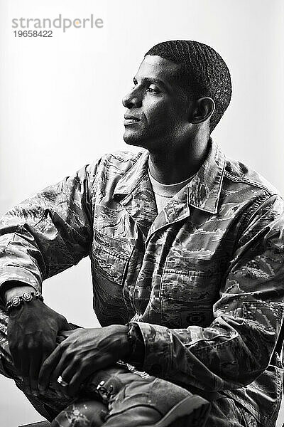 Ein afroamerikanischer  männlicher Luftwaffen-Sicherheitsflieger in Uniform sitzt für ein Schwarz-Weiß-Profilporträt vor weißem Hintergrund.