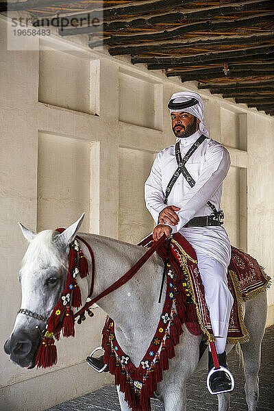 Mann in traditioneller arabischer Kleidung reitet Pferd im Souq Waqif  Doha  Katar