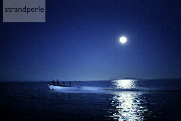 An einem ruhigen Morgen in der Bucht von Magdalena  Baja  Mexiko  schneidet ein Panga durch die Spiegelung des Mondes. 2007. (Bewegungsunschärfe)