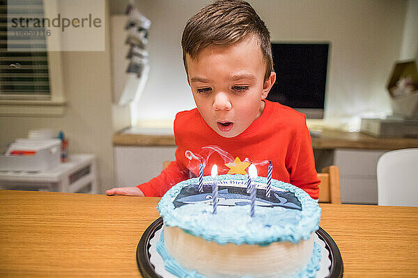 Sechsjähriger Junge bläst Kerzen auf seinem Haifischkuchen aus