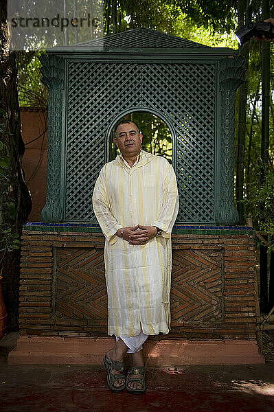 Ein Mann in traditioneller nahöstlicher Kleidung steht in einem marokkanischen Garten.