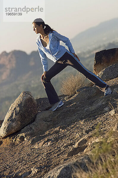 Eine Frau macht Dehnübungen  bevor sie auf dem Camelback Mountain in Arizona joggen geht.