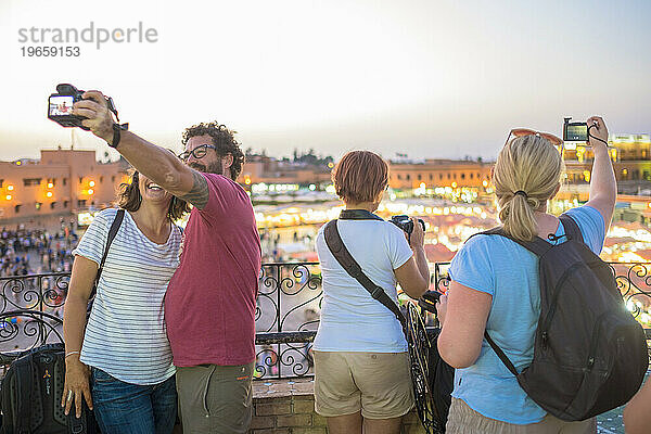 Touristen machen nachts Selfies über dem geschäftigen Djemaa El Fna