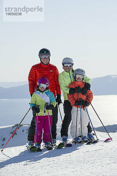 Eine vierköpfige Familie lächelt mit Lake Tahoe im Hintergrund beim Skifahren im Skigebiet Alpine Meadows am Nordufer des Lake Tahoe  Kalifornien.