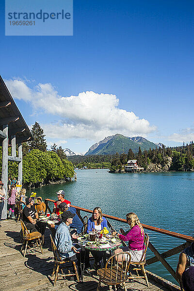 An einem sonnigen Tag sitzen Menschen an Tischen in einem Restaurant in der abgelegenen Stadt Halibut Cove  Alaska.