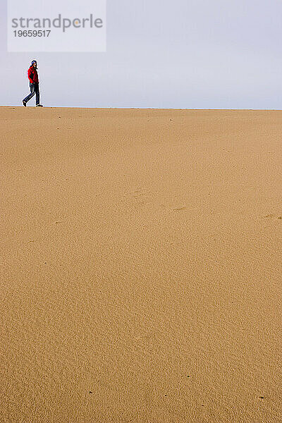 Eine junge Frau Anfang dreißig spaziert durch die Sanddünen von Florence  Oregon  USA.