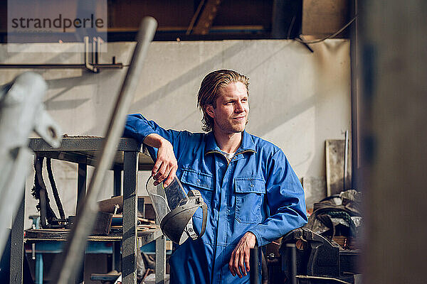 Nachdenklicher Mann mit Helm in der Fabrik