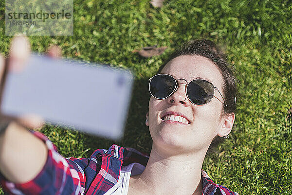 Oben Ansicht einer jungen lächelnden Hipster-Frau  die auf Gras liegt