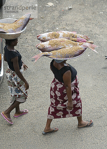 Zwei liberianische Frauen tragen große Fische auf dem Kopf