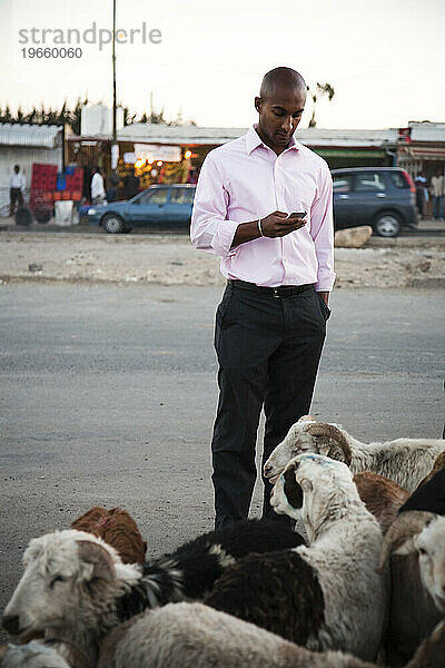 Ein junger äthiopischer Mann nutzt sein Mobiltelefon auf einem Ziegenmarkt in den verarmten Gebieten Äthiopiens.
