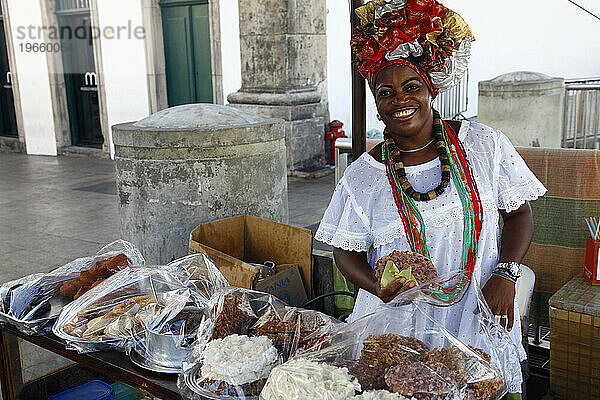 Bahia-Frau in traditioneller weißer Kleidung (Baiana) verkauft Streetfood im Pelourinho-Viertel  Salvador  Bahia  Brasilien.