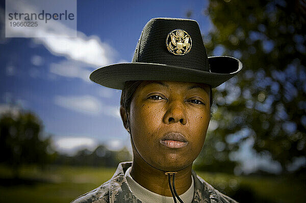 A drill sergeant wears a traditional campaign hat and camouflage uniform while looking tough.