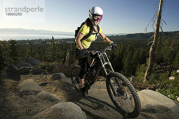 Eine Frau beim Mountainbiken auf dem Van Sickle Trail mit Lake Tahoe im Hintergrund in South Lake Tahoe  Kalifornien.