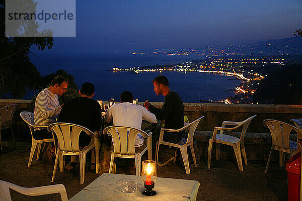 Menschen sitzen in einem Restaurant im Freien in Taormina  Sizilien  Italien