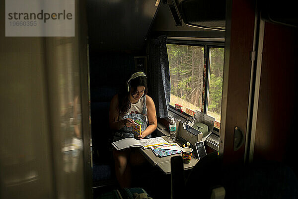 Junge Frau fährt mit Malbuch im Personenzug