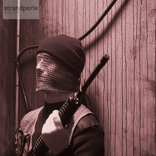 Seitenansichtporträt eines Soldaten in Tarnkleidung  Hut und Gesichtsmaske  der ein Gewehr hält. (Veröffentlichungscode: rrk_mr27)