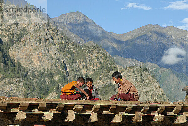 Drei junge Mönche spielen Carrom in Nepal.