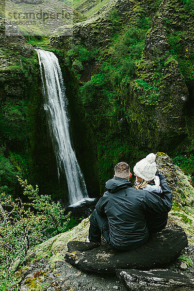 Frau lächelt Ehemann bei Wanderung mit Blick auf Wasserfallklippe an