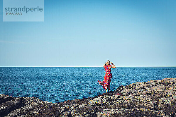 Silhouette einer Frau in Rot am sonnigen Tag des Ozeans in Skandinavien