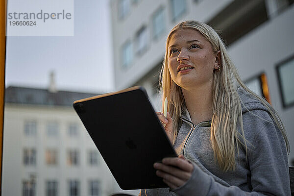 Glückliche Frau hält Tablet-PC in der Stadt