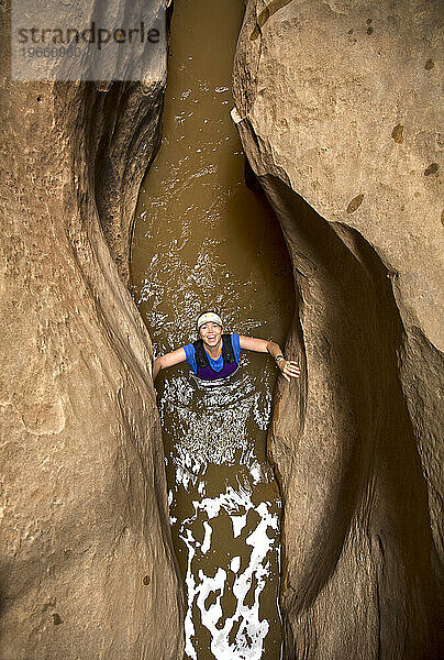 Eine Frau watet durch Wasser in einem Wüsten-Slot-Canyon in Utah.