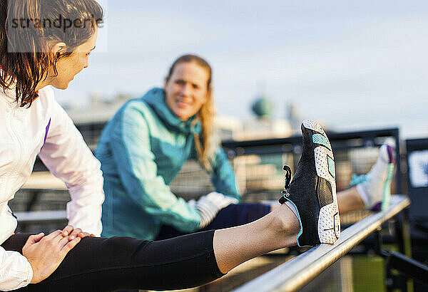 Zwei Läuferinnen dehnen ihre Kniesehnen nach dem Joggen in der Nähe von Puget Sound  Seattle  Washington State  USA