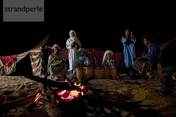 Lokale Stammesangehörige singen und tanzen an einem Beduinenlagerfeuer in der großen offenen Sahara.