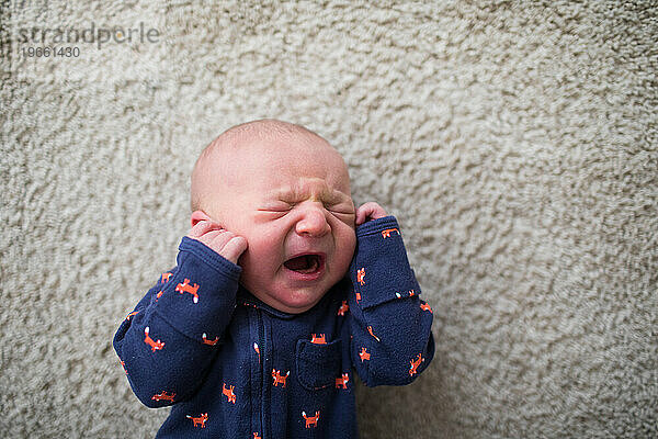 Draufsicht auf ein neugeborenes Baby  das auf dem Boden weint