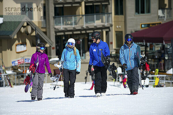 Eine Gruppe Snowboarder geht mit ihrem Snowboardlehrer im Dorf Kirkwood Mountain Resort in Kirkwood  Kalifornien  spazieren.