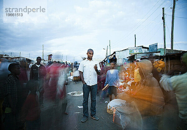 Ein junger äthiopischer Mann steht auf einem überfüllten Stadtmarkt in einem verarmten Viertel von Harar  Äthiopien  und überprüft seine E-Mails