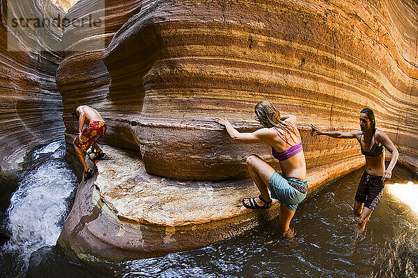 Drei Menschen klettern einen Slot Canyon mit fließendem Wasser hinunter  Deer Creek  Grand Canyon  Arizona.