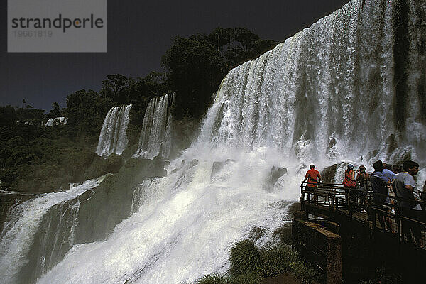 Eine Gruppe Touristen steht voller Ehrfurcht vor den Iguazu-Wasserfällen in Argentinien.