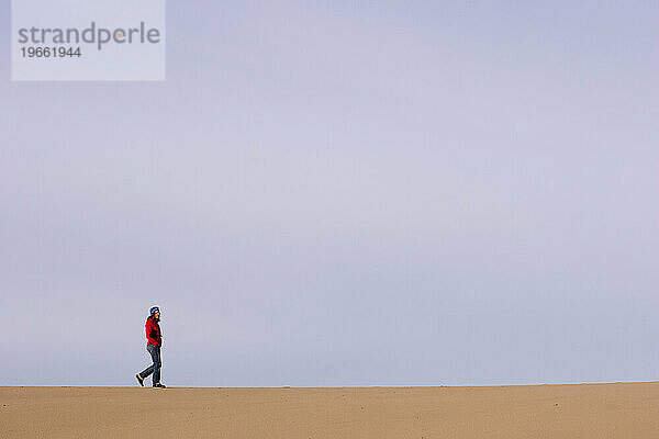 Eine junge Frau Anfang dreißig spaziert durch die Sanddünen von Florence  Oregon  USA.