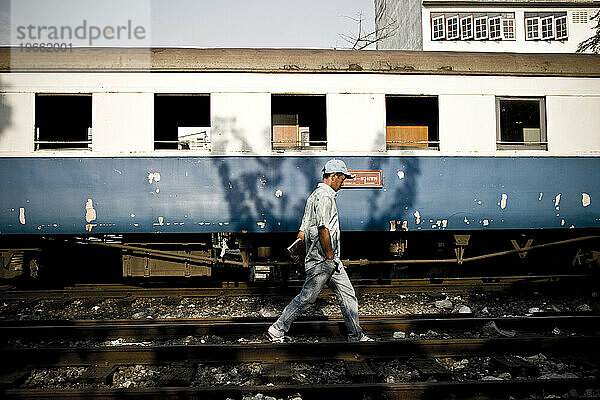 Ein Mann  der in den Slums neben einem Zug läuft.