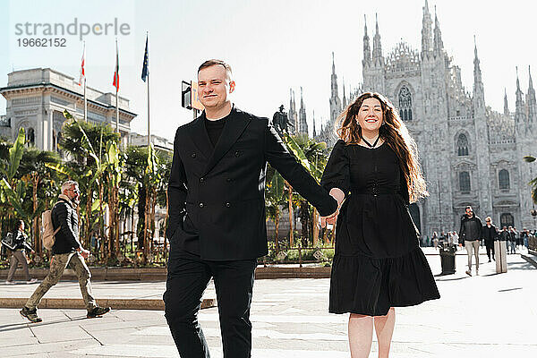 Stilvolles Mädchen und Mann in Schwarz  die im Zentrum von Mailand spazieren gehen