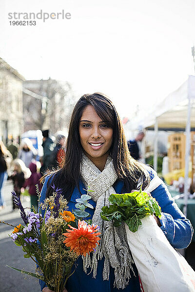 Eine junge Frau kauft an einem kühlen Herbsttag auf dem Ballard Farmer's Market frische Produkte ein.