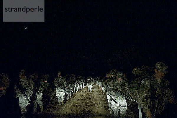 Während einer Feldübung marschieren Soldaten mitten in der Nacht eine unbefestigte Straße entlang.